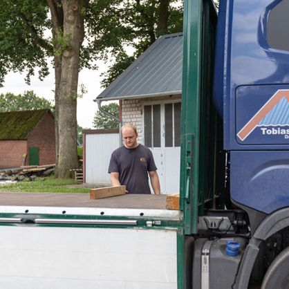 Geschaeftsfuehrer legt Holz auf Lkw