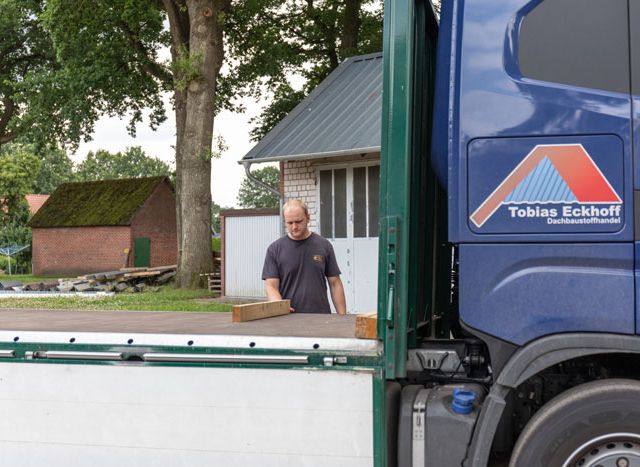 Geschaeftsfuehrer legt Holz auf Lkw